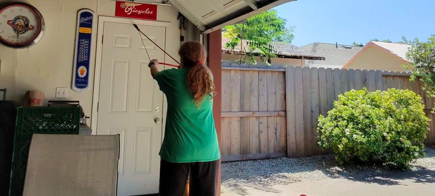 Woman doing mobility and flexibility training with a resistance band row in an open garage in Chico, CA — recovery and specialty personal training with Gym Truck Chico